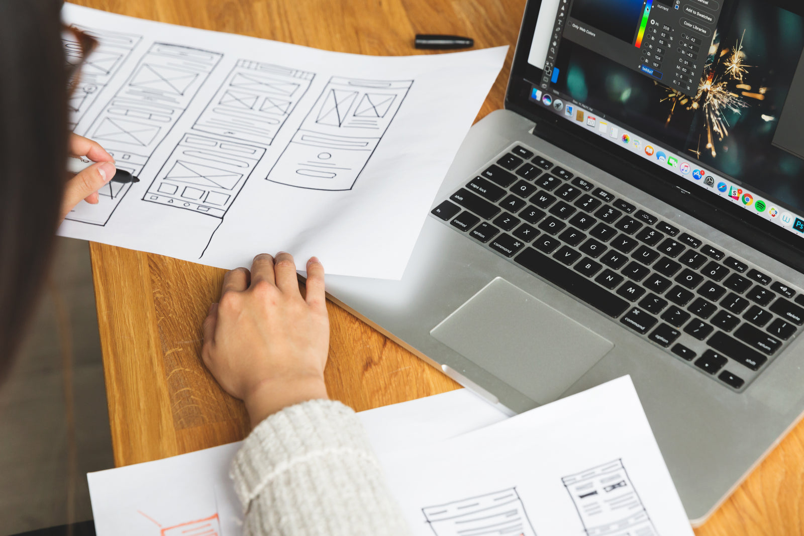 Illustrative stock  -  designer reviewing wireframes at a well-lit desk. Not ReStructure AI output or staff.